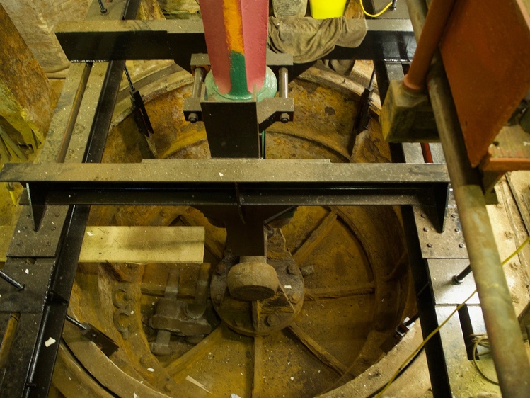 Looking down on some circular machinery, covered in dirt and rust. The top of the machinery has some red and green paint.